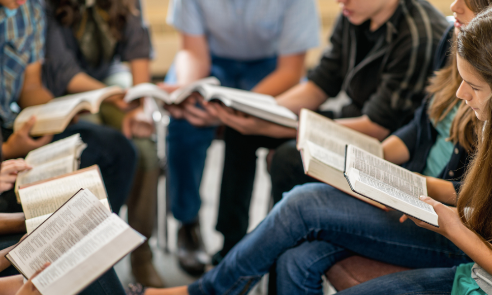 People sitting in a semicircle reading from the Bible