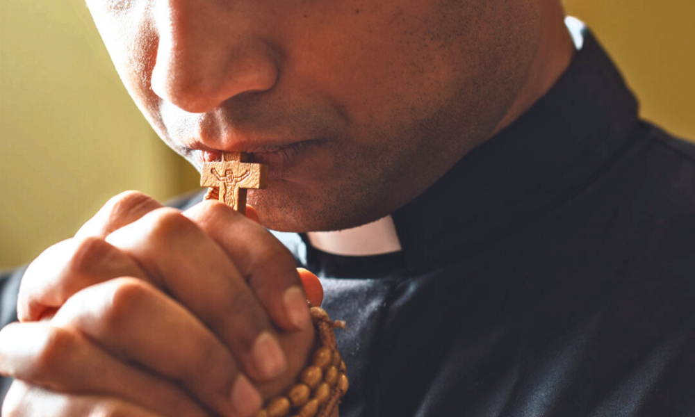 Priest praying with rosary